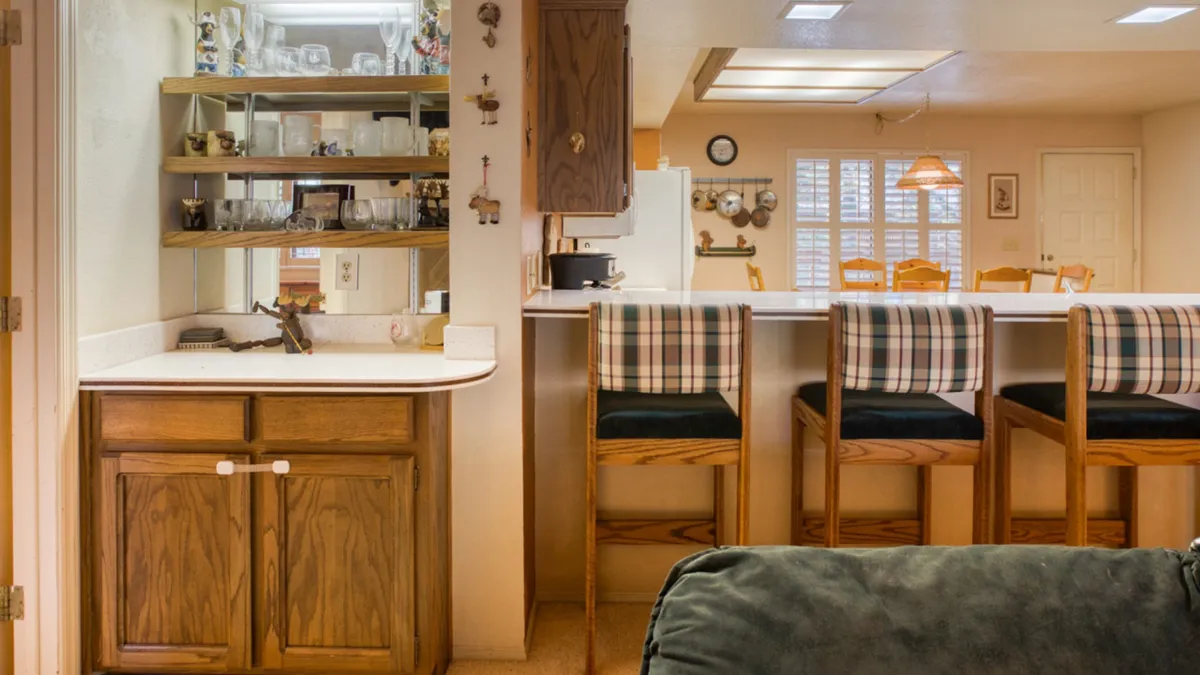 The image presents a countertop display with sparkling glassware, plaid-cushioned bar stools, and an open view leading directly into the kitchen area. It conveys a mood of celebration and togetherness, ideal for both casual and special occasions.